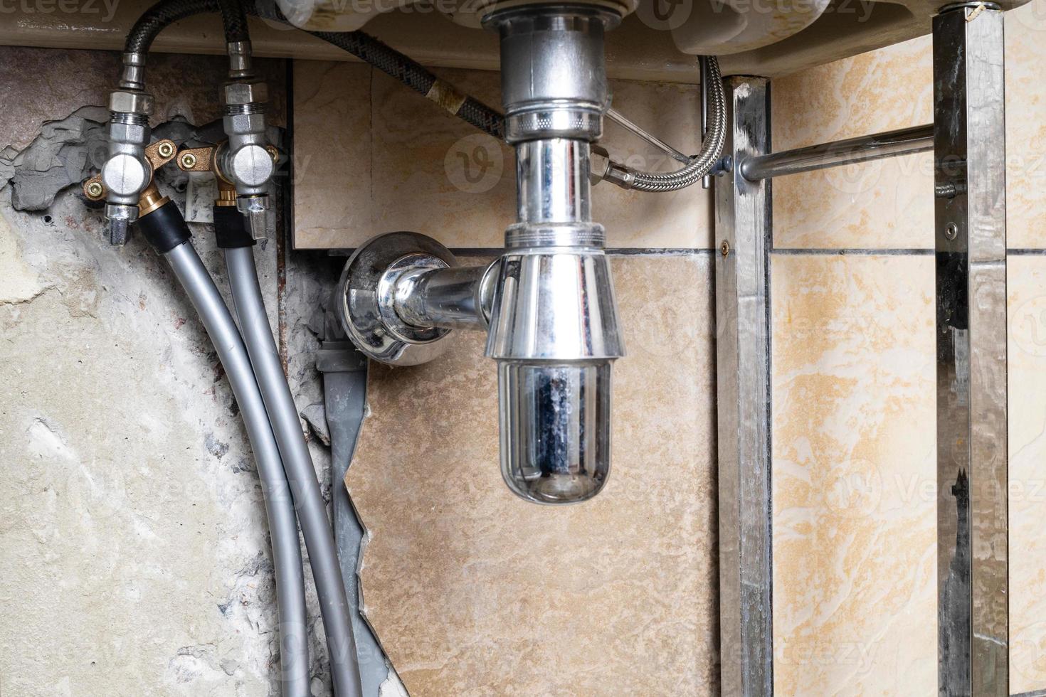 tubulações de água conectadas à válvula da pia no banheiro foto