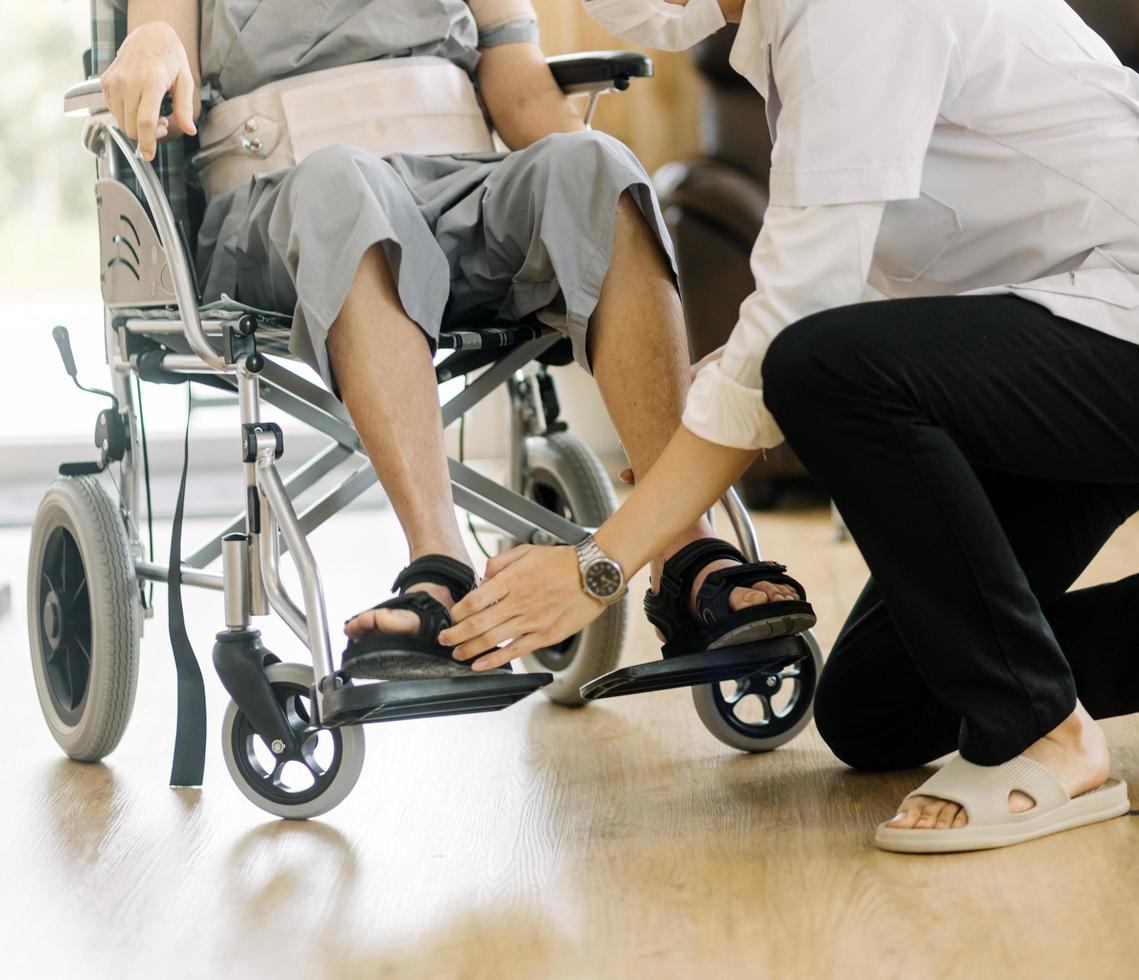 médico ou enfermeiro cuidador com homem sênior em cadeira de rodas usando máscaras protetoras em casa ou lar de idosos foto