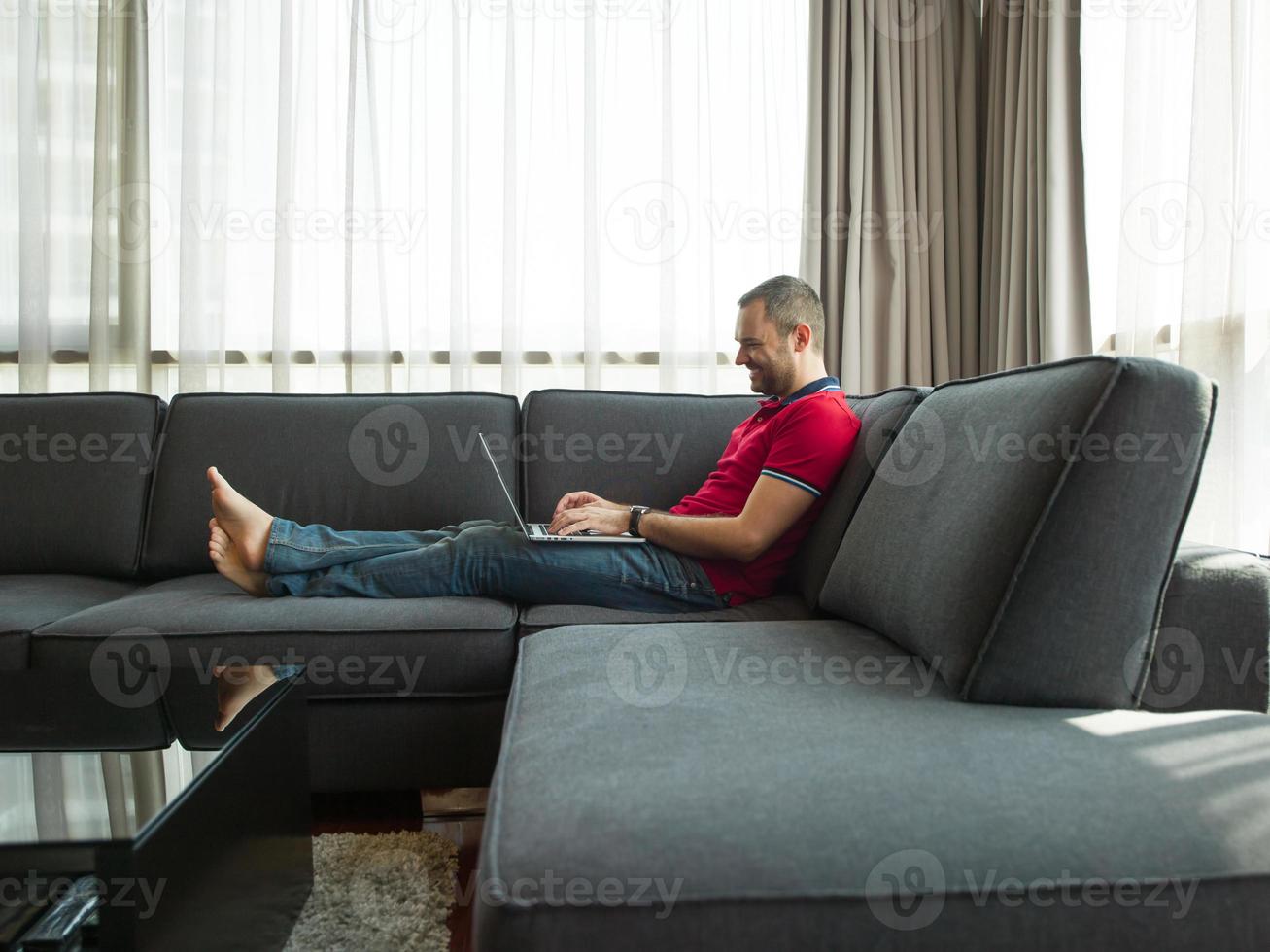 homem usando laptop na sala de estar foto