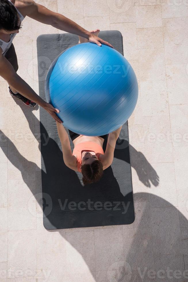 mulher e personal trainer fazendo exercício com bola de pilates foto