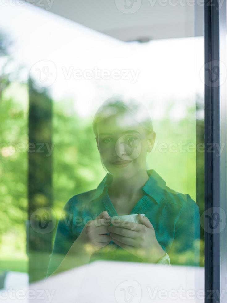 jovem tomando café da manhã pela janela foto