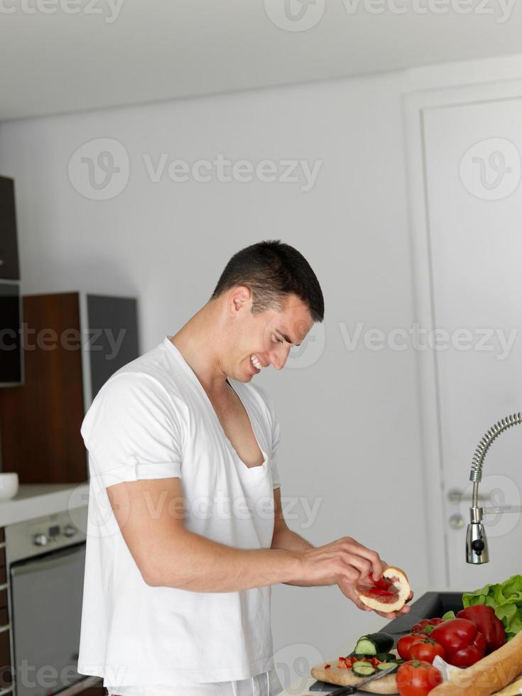 homem cozinhando em casa preparando salada na cozinha foto