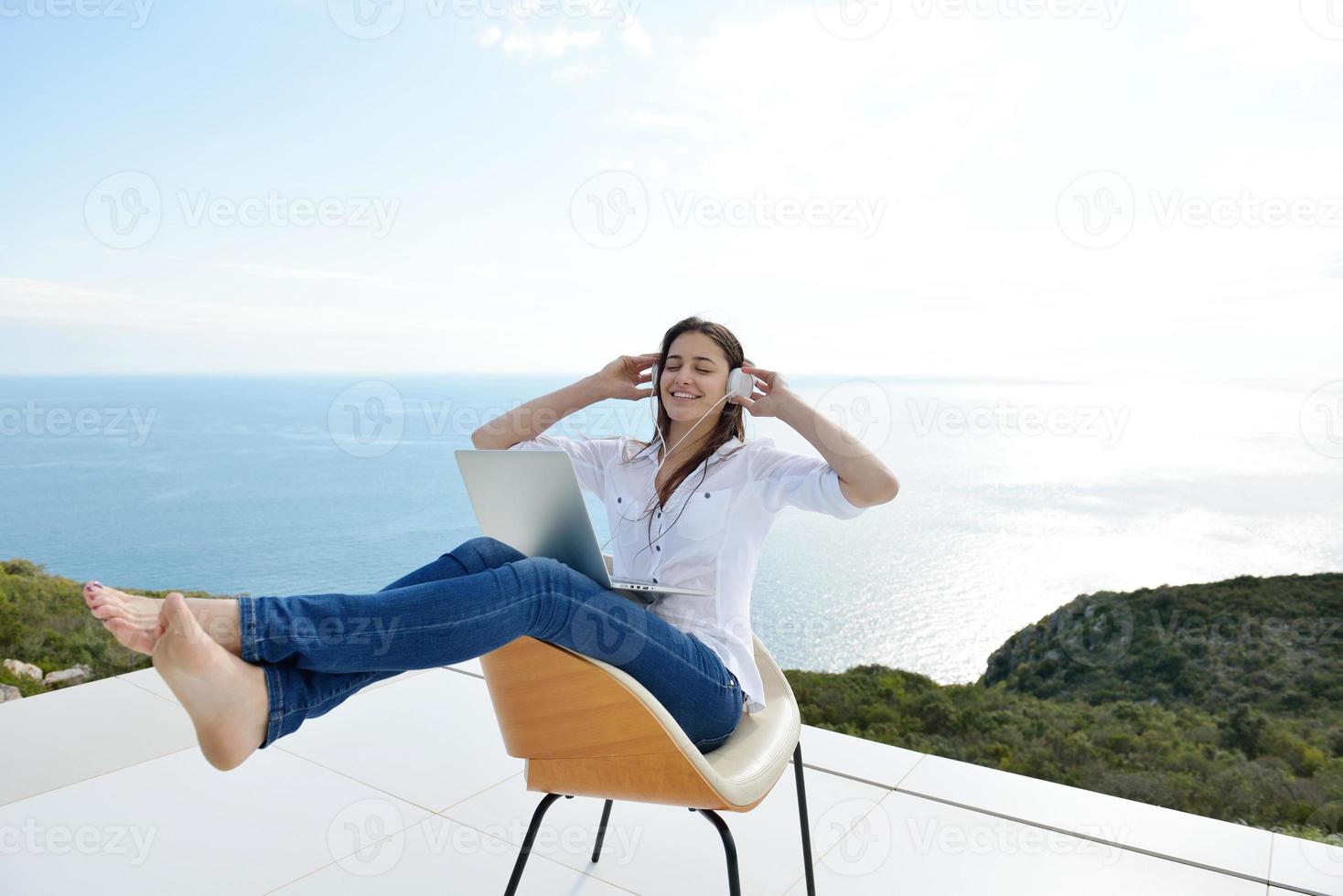 jovem relaxada em casa trabalhando no laptop foto