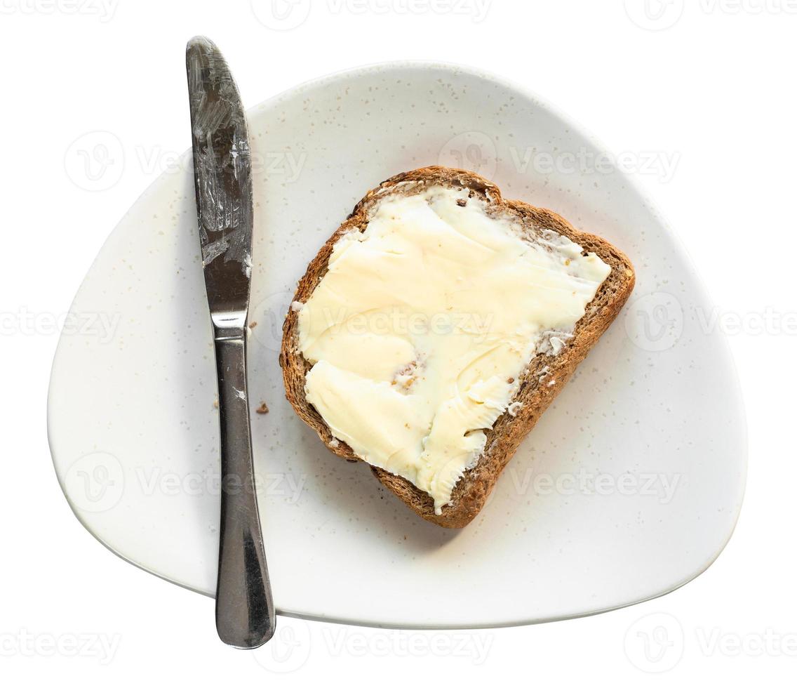 sanduíche com manteiga e faca no prato isolado foto