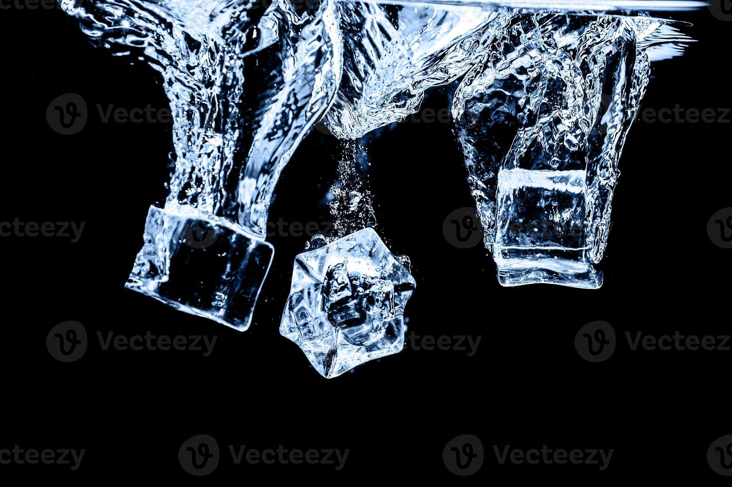 cubos de gelo na água no fundo escuro do estúdio. o conceito de frescura com frieza de cubos de gelo. foto