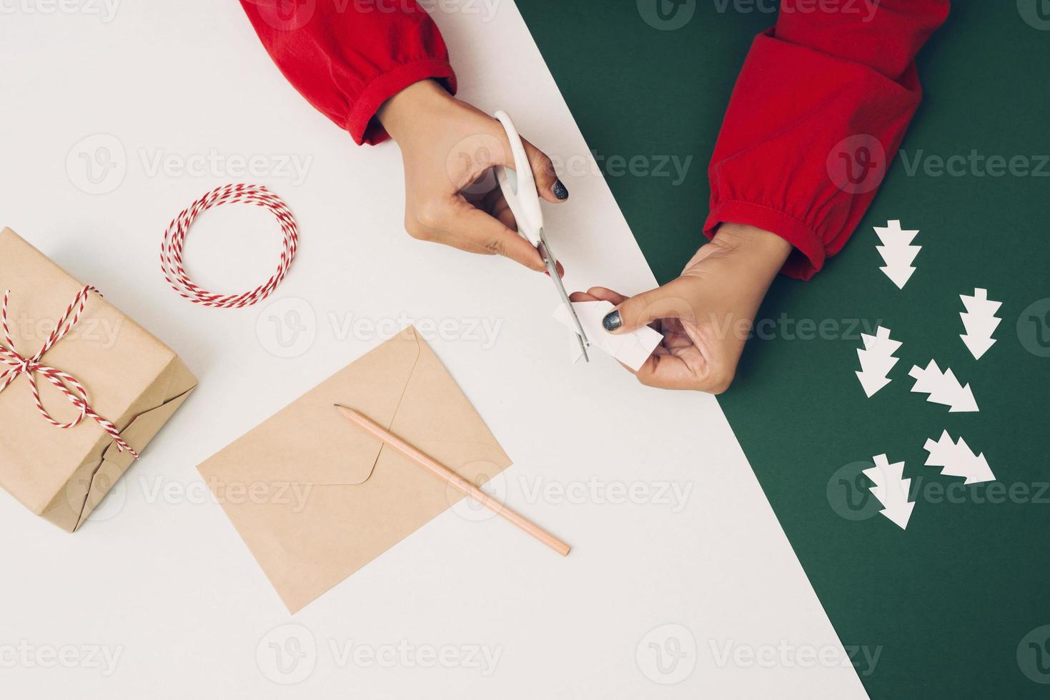 mulher cortando papel de árvore de natal com envelope e papel colorido. noel diy foto
