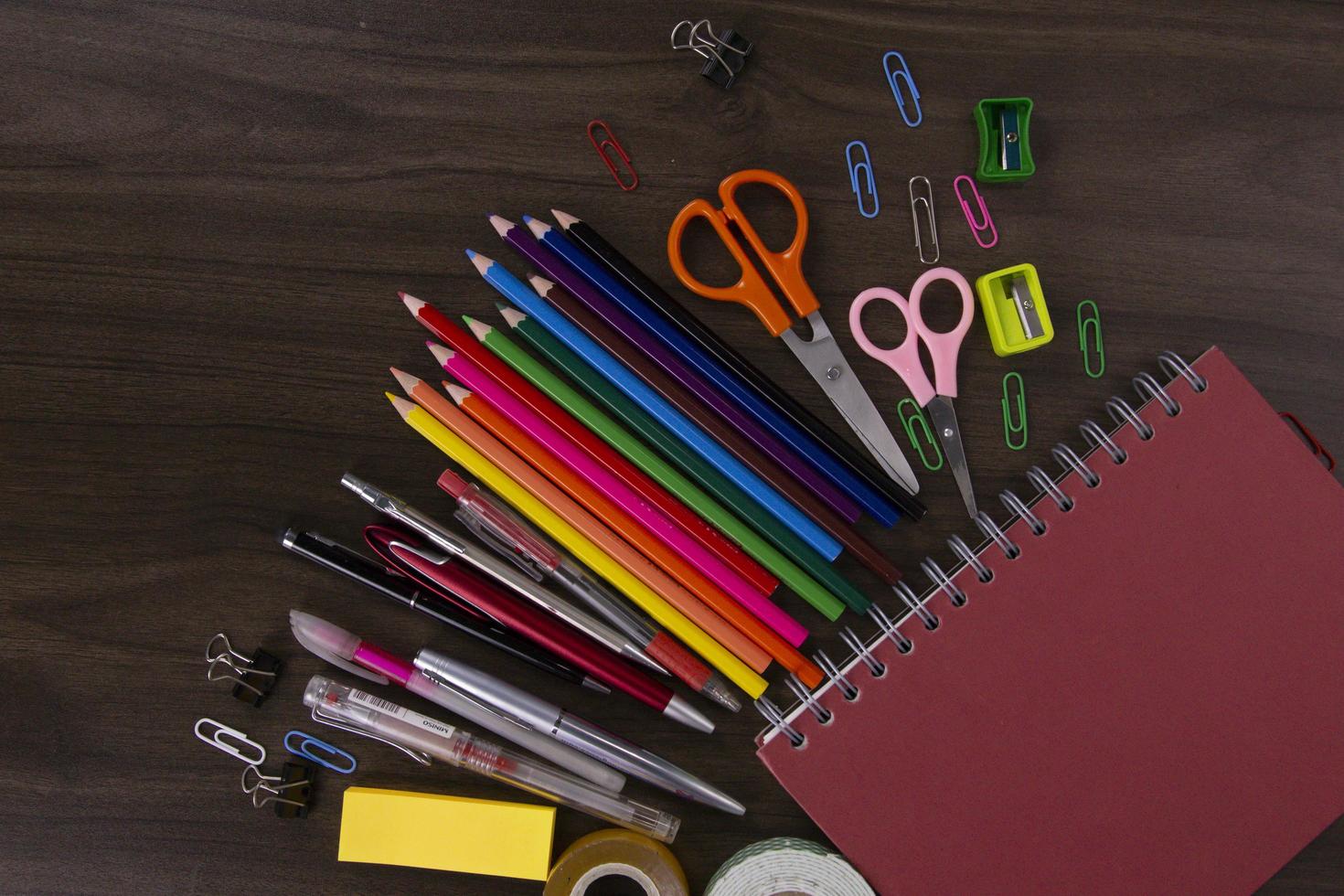 livros vermelhos com lápis de cor e elementos de educação, volta aos conceitos de escola em fundo escuro de madeira. usado em cartazes, brochuras e anúncios impressos foto