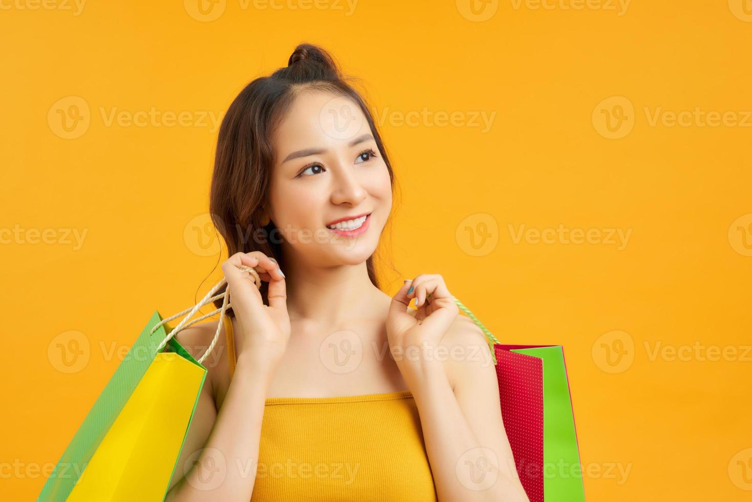 retrato de menina bonita asiática feliz segurando sacolas de compras olha isolado sobre fundo azul, venda de temporada de sexta-feira negra, conceito de venda de verão colorido de compras. foto