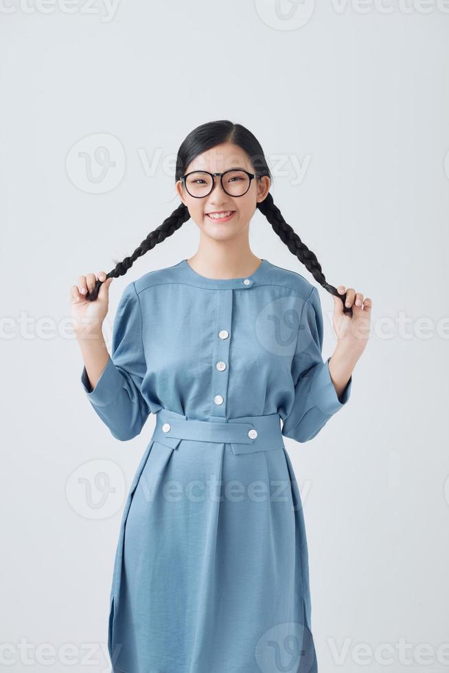linda garota adolescente com duas tranças de cabelo de tranças de mãos dadas e posando para a câmera foto