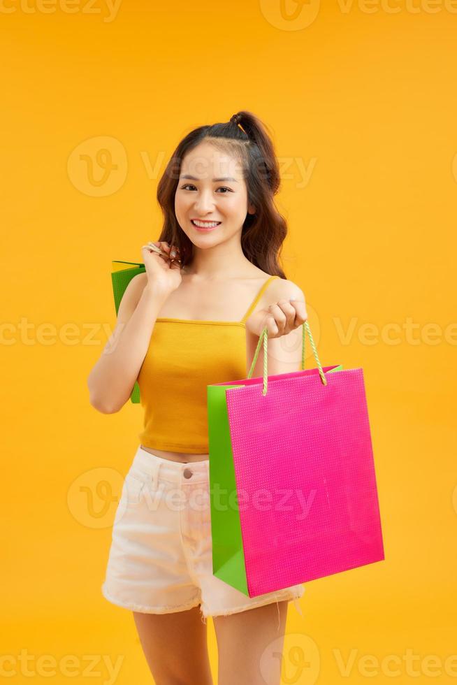 retrato de menina bonita asiática feliz segurando sacolas de compras olha isolado sobre fundo azul, venda de temporada de sexta-feira negra, conceito de venda de verão colorido de compras. foto