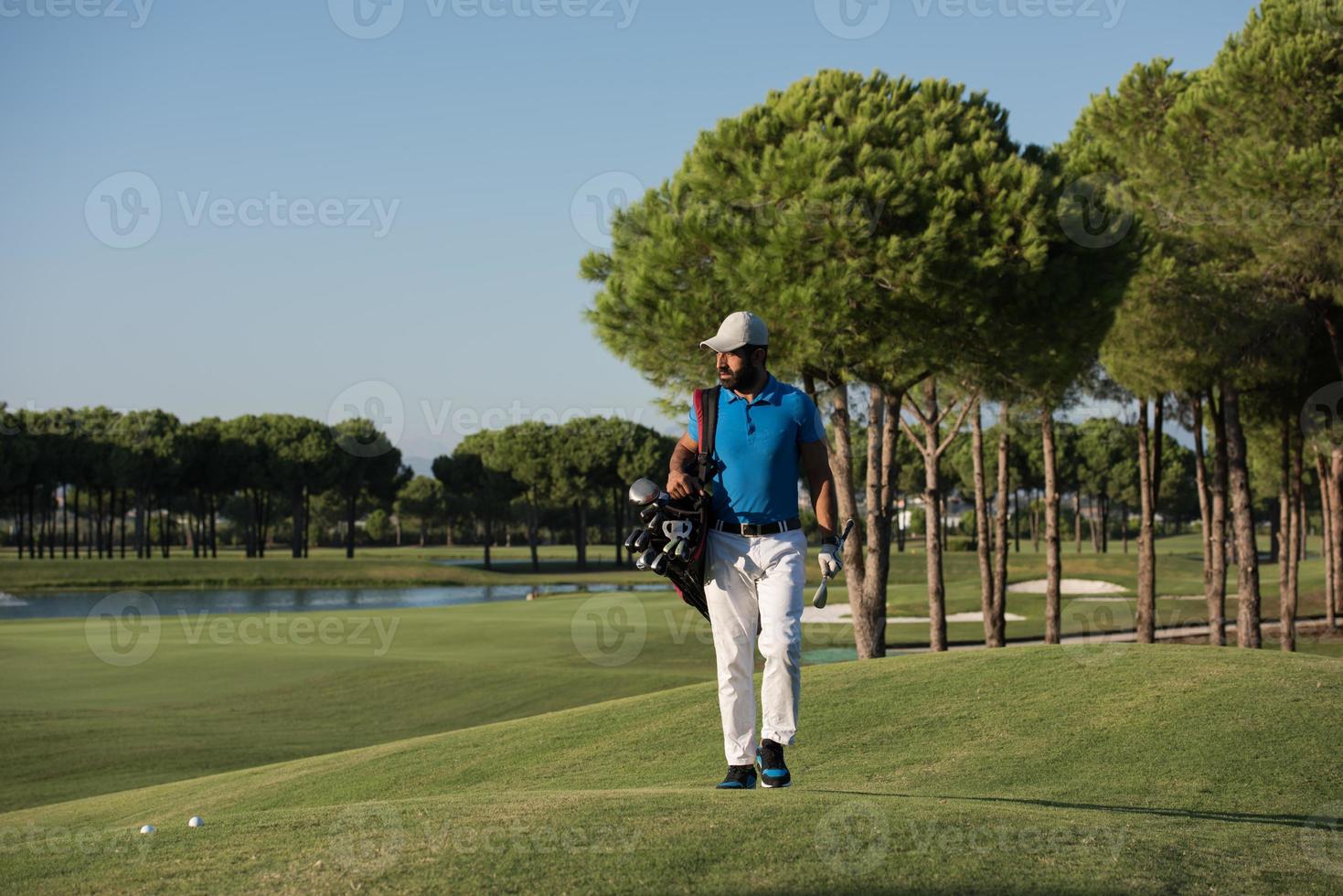 jogador de golfe andando e carregando bolsa foto