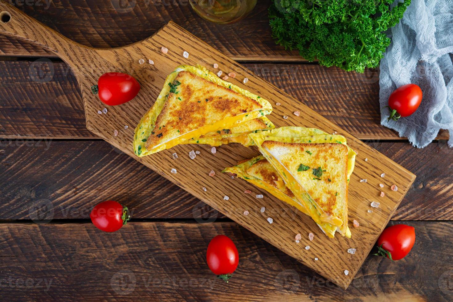 rabanada assada com presunto, ovo, ervas e queijo cheddar. delicioso sanduíche de café da manhã grelhado foto