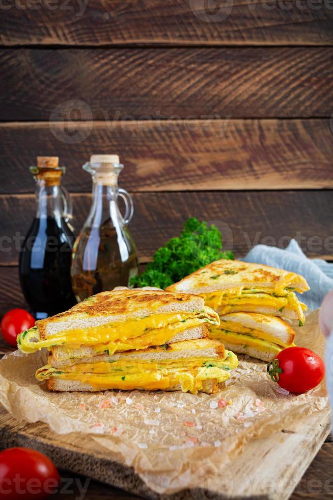 rabanada assada com presunto, ovo, ervas e queijo cheddar. delicioso sanduíche de café da manhã grelhado foto