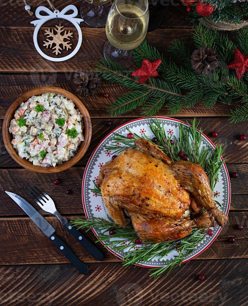 frango inteiro assado ou peru para o natal. mesa de ano novo com decoração, frango assado caseiro, vinho e salada. vista do topo foto