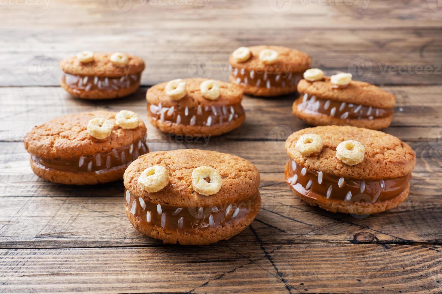 biscoitos com pasta de creme em forma de monstros para festa de halloween. carinhas caseiras engraçadas feitas de biscoitos de aveia e leite condensado fervido. foto