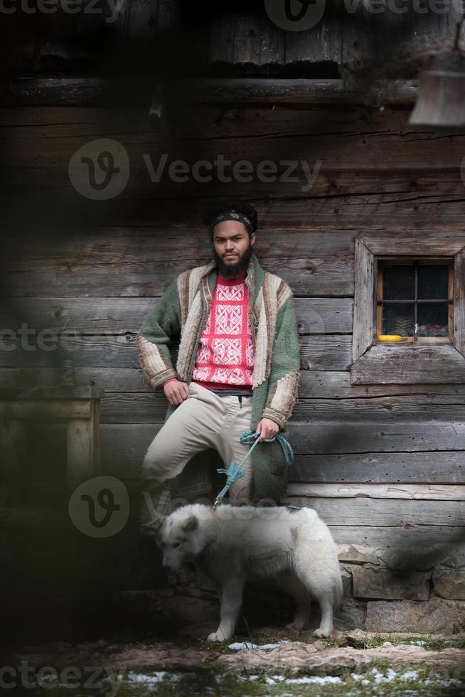 hipster com cachorro na frente da casa de madeira foto
