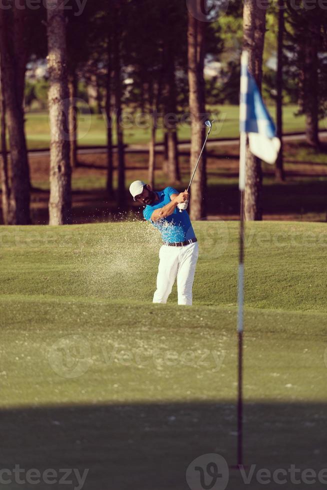 golfista profissional acertando um tiro de bunker de areia foto