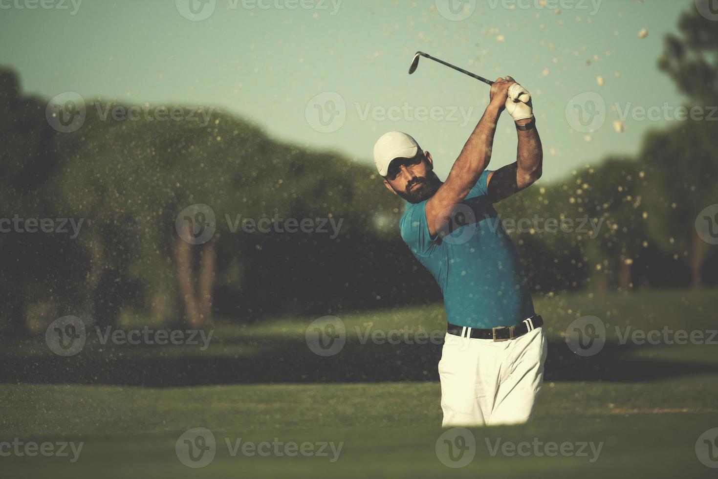 golfista profissional acertando um tiro de bunker de areia foto