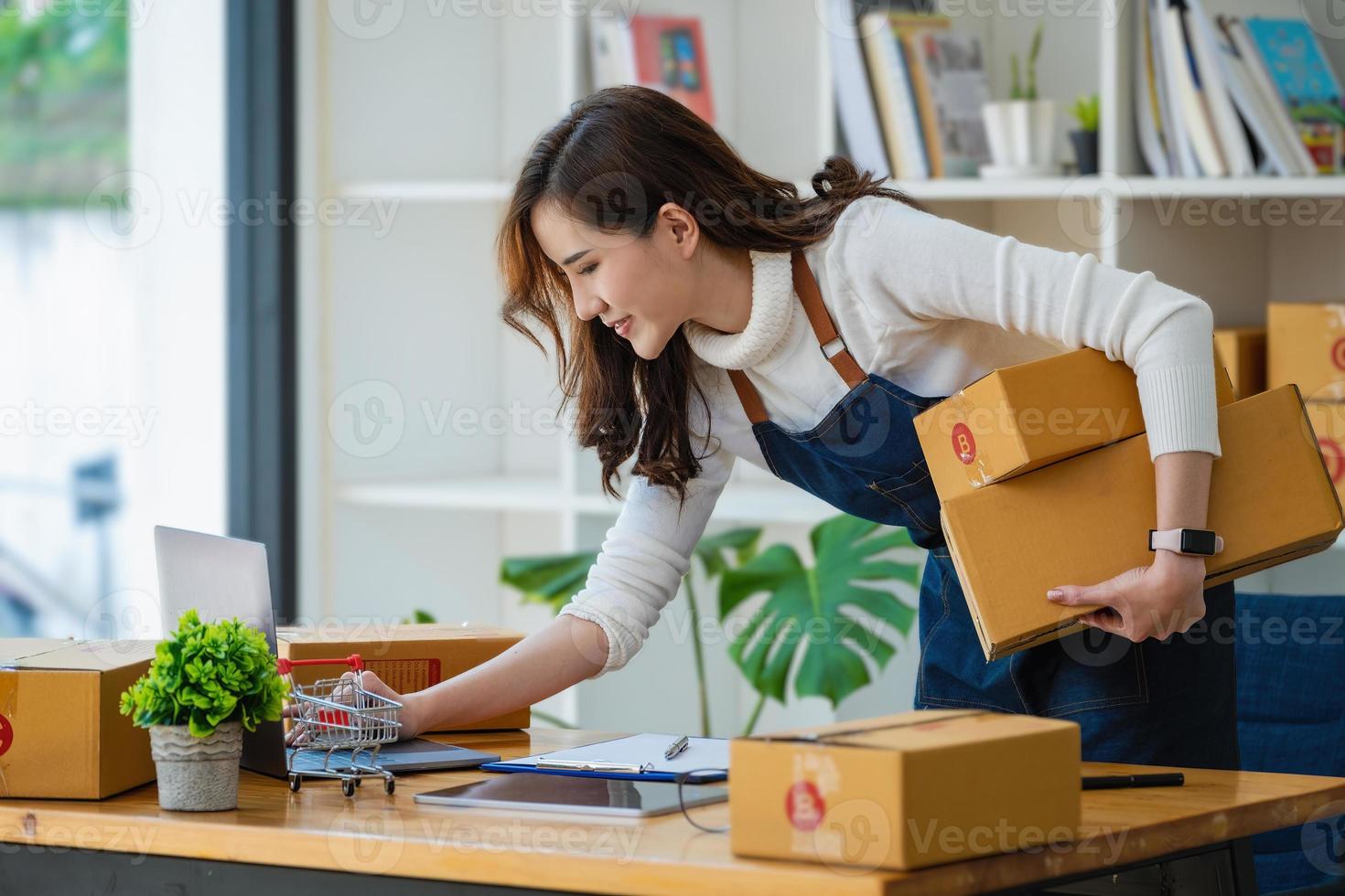 trabalho a partir de casa. mulheres felizes que vendem produtos on-line iniciam uma pequena empresa usando o laptop para calcular preços e se preparar para a postagem. foto