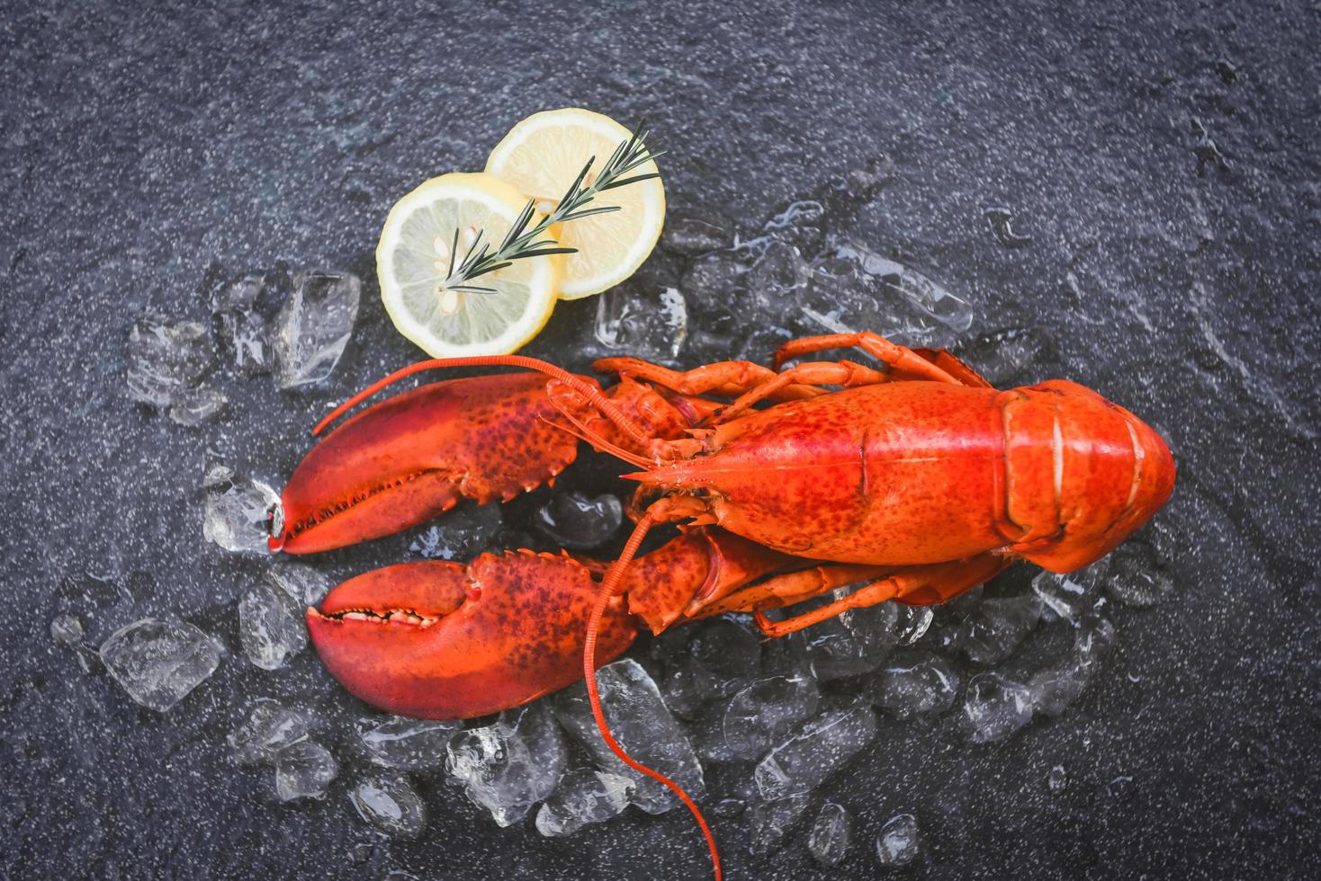 comida de lagosta fresca em um fundo de placa preta jantar de lagosta vermelha frutos do mar com especiarias de ervas alecrim limão servido mesa e gelo no restaurante comida gourmet lagosta cozida saudável cozida foto