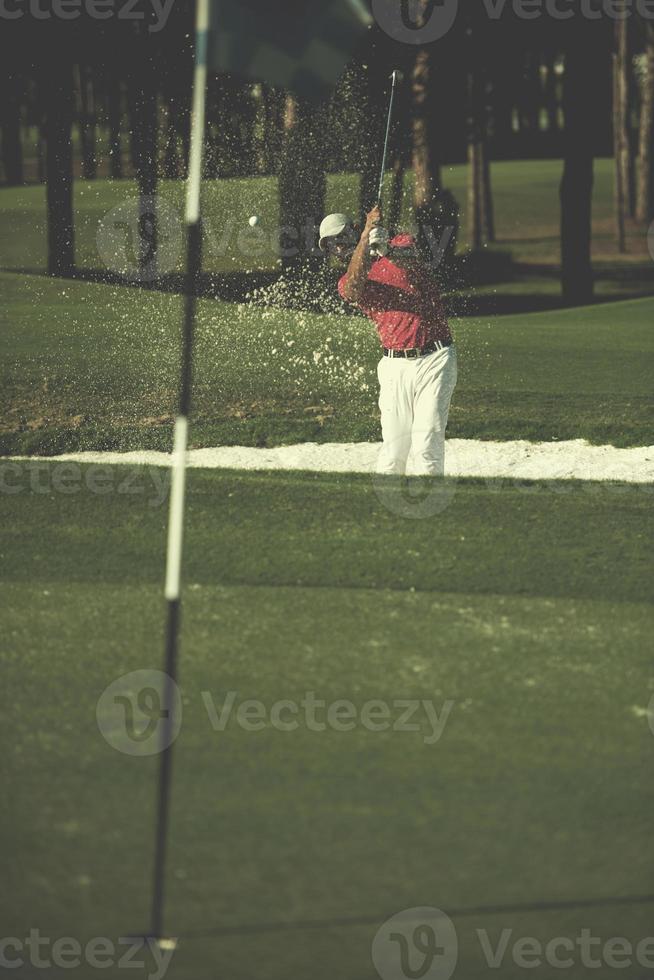 golfista acertando um bunker de areia foto