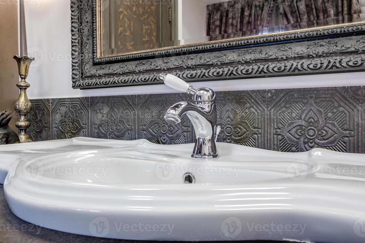 torneira de água de metal com pia e torneira para ligar e regular a água fria ou quente no banheiro caro. foto