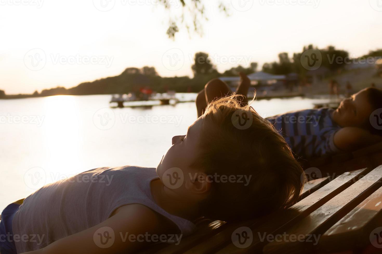 meninos relaxados desfrutando no pôr do sol de verão na praia. foto