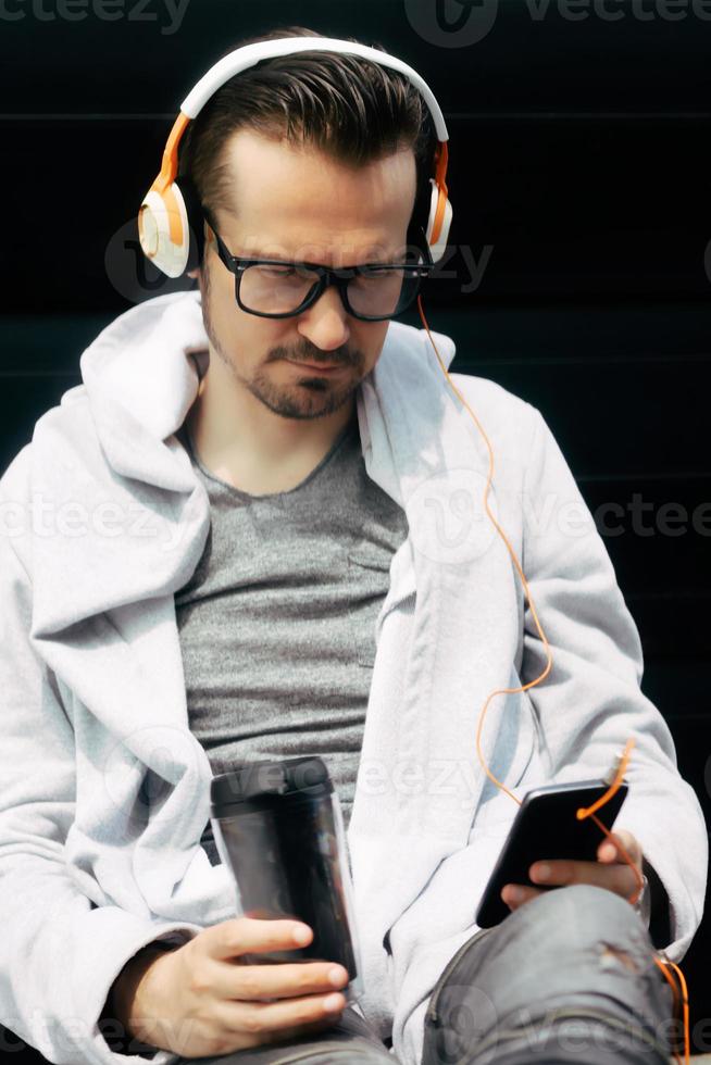 homem pensativo mandando mensagens no celular enquanto toma café para viagem ao ar livre. foto