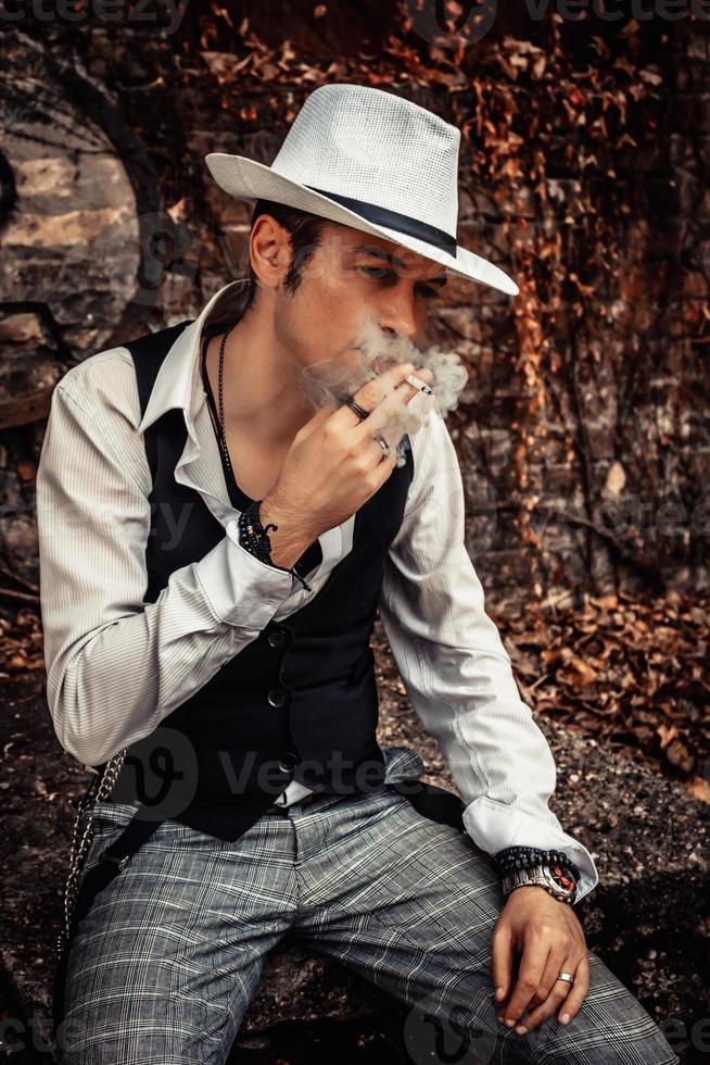 homem com estilo fedora fumando um cigarro. foto