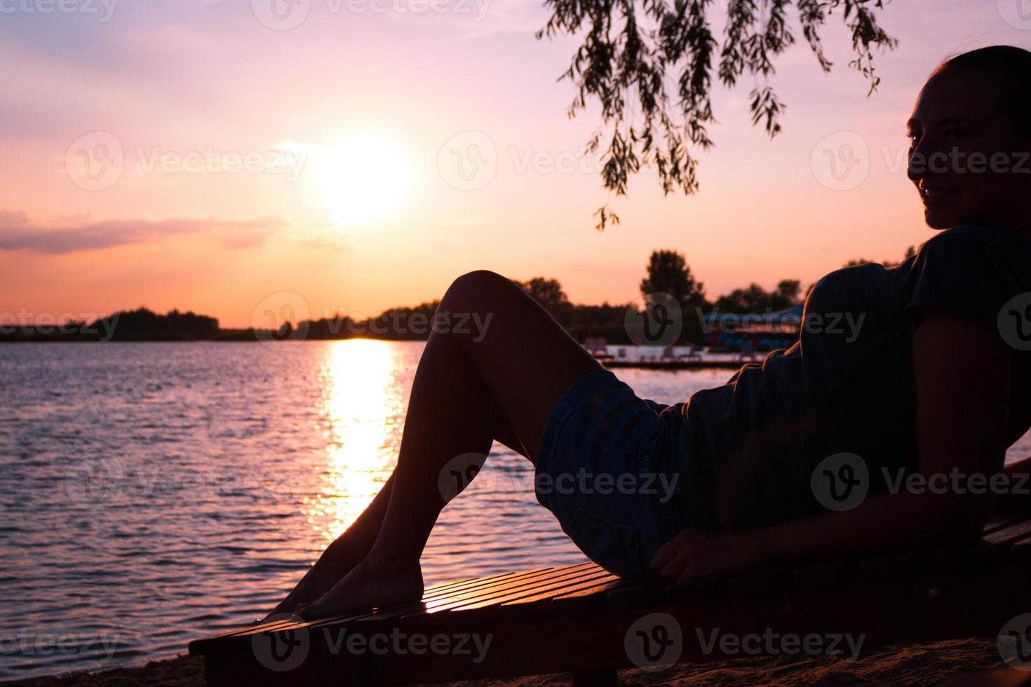 silhueta de mulher relaxante na praia ao pôr do sol. foto