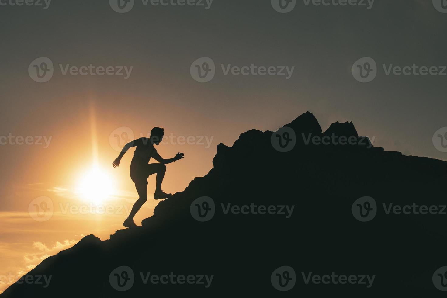 um homem corre entre as rochas em um pôr do sol colorido da montanha foto