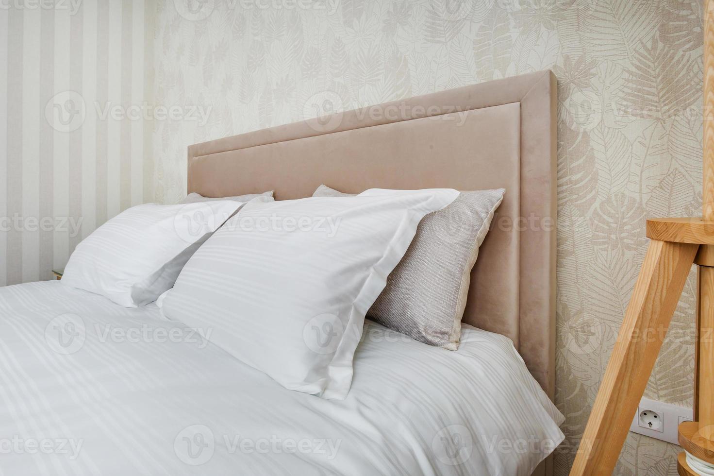 almofadas na cama principal no interior do quarto de luxo moderno em estúdios em estilo de cor clara foto