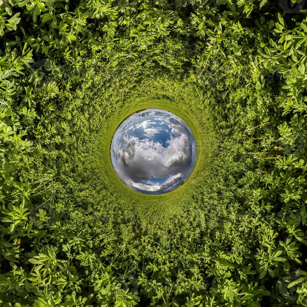 inversão do pequeno planeta azul transformação do panorama esférico 360 graus. vista aérea abstrata esférica no campo de grama verde com lindas nuvens impressionantes. curvatura do espaço. foto
