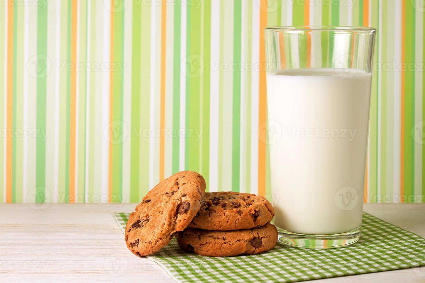 saborosos biscoitos e copo de leite sobre fundo verde foto