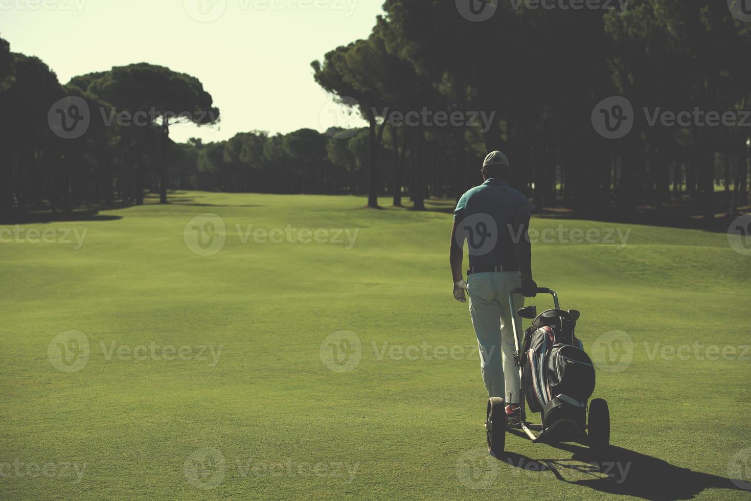 jogador de golfe andando com bolsa de rodas foto