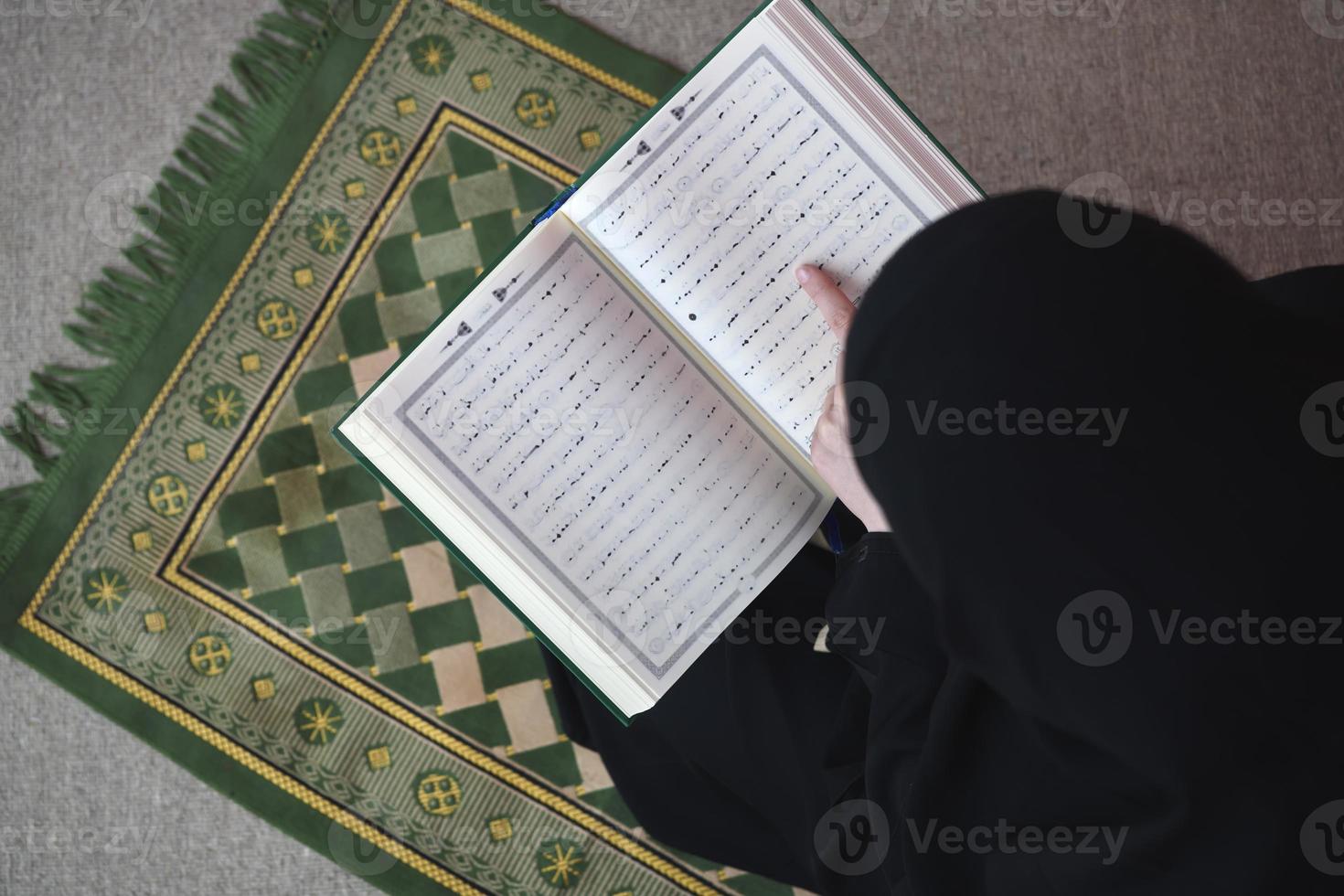 mulher do Oriente Médio orando e lendo o Alcorão Sagrado foto