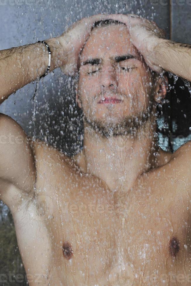 homem bonito sob o chuveiro do homem foto
