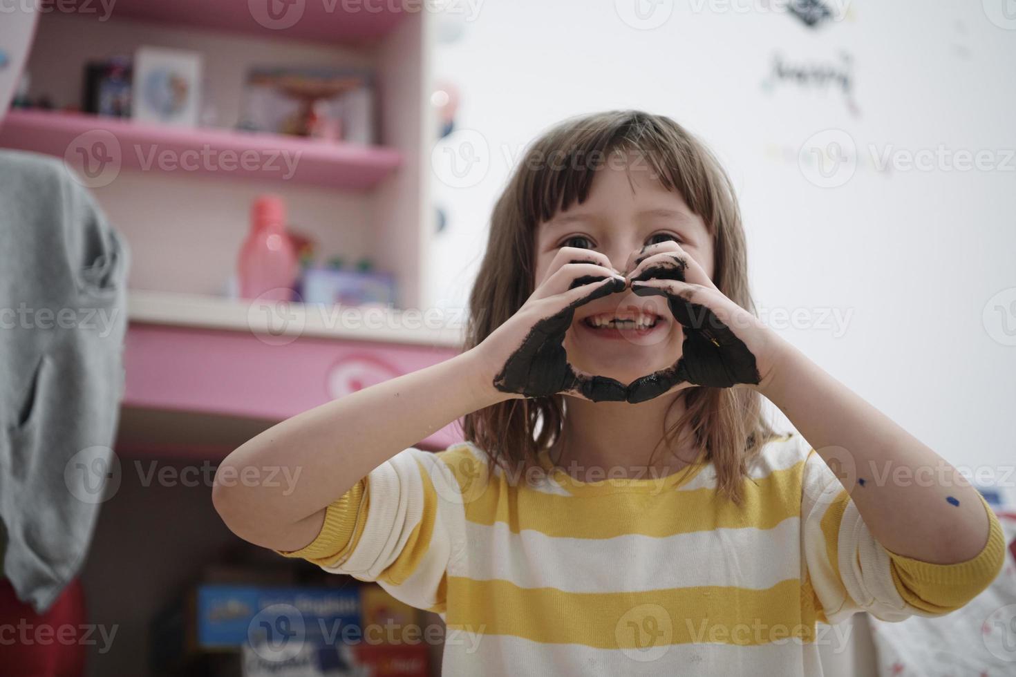 menina bonitinha em casa pintando com as mãos foto