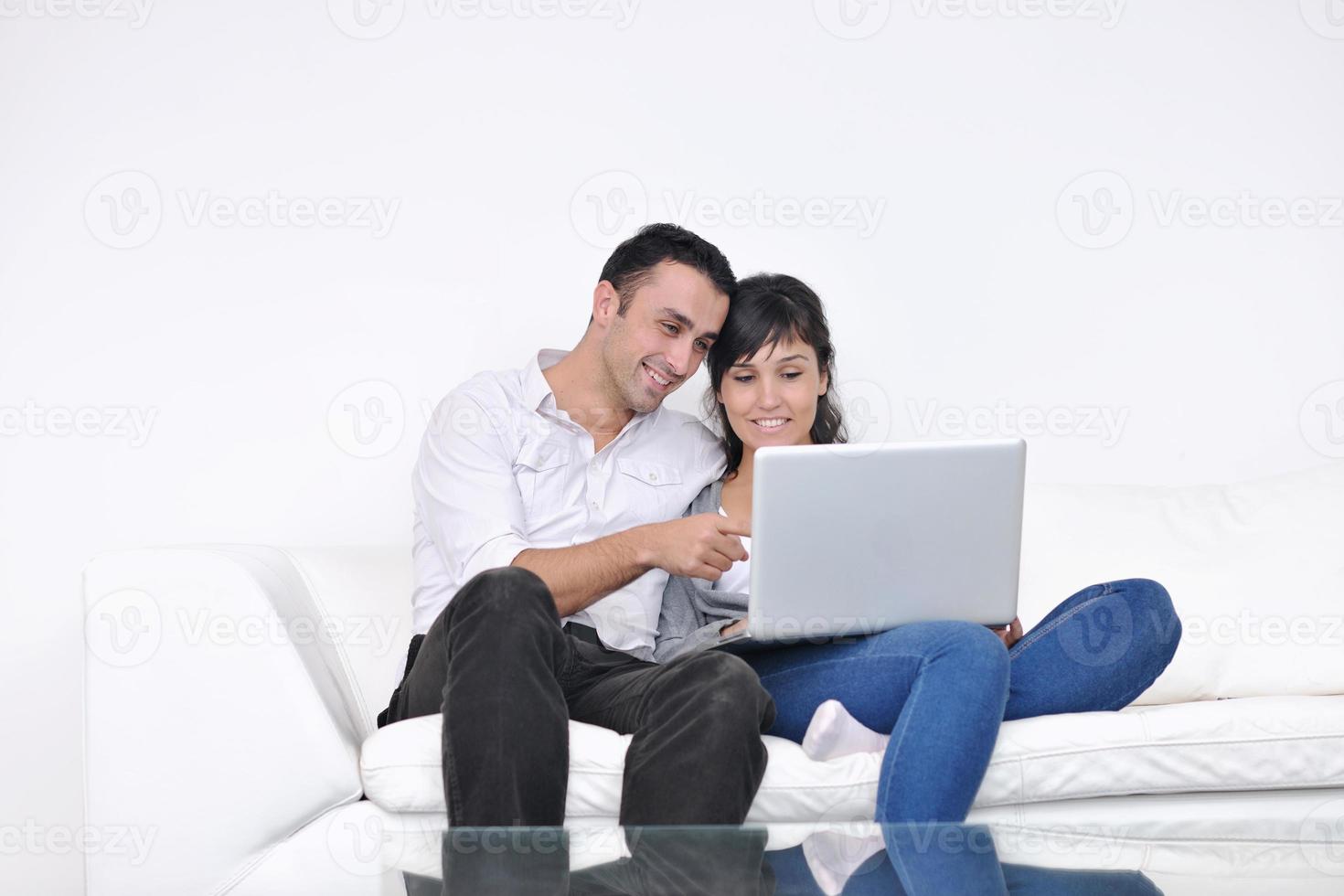 casal alegre relaxa e trabalha no computador portátil em casa moderna foto