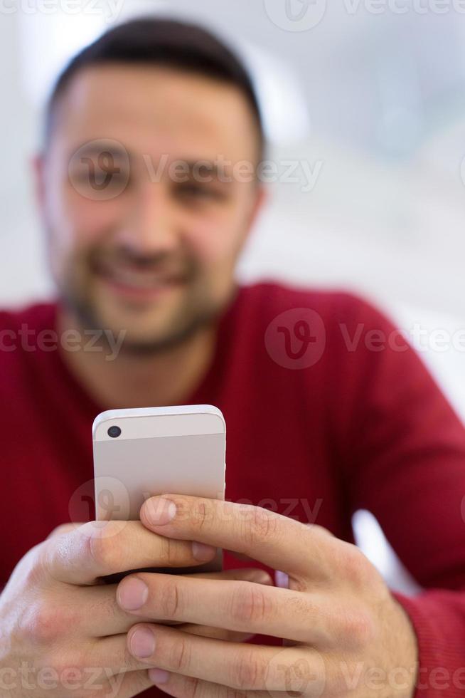 jovem usando um telefone celular em casa foto