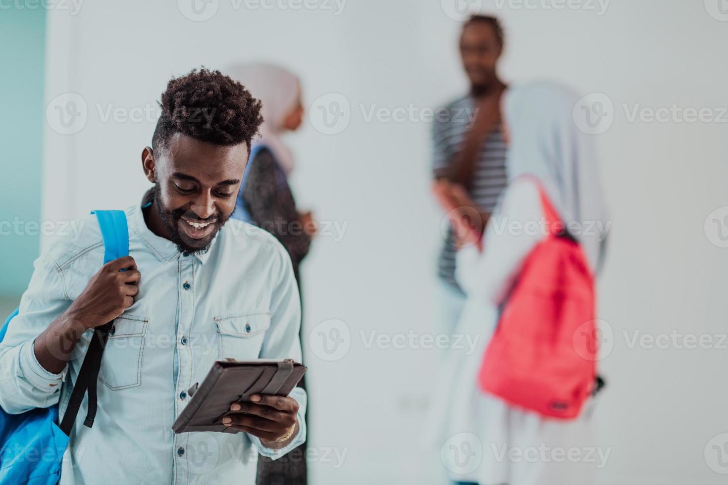 estudante de estilo de vida universitário segurando um computador tablet e sorrindo em pé contra a universidade com seus amigos tem uma reunião de equipe em segundo plano. foto de alta qualidade