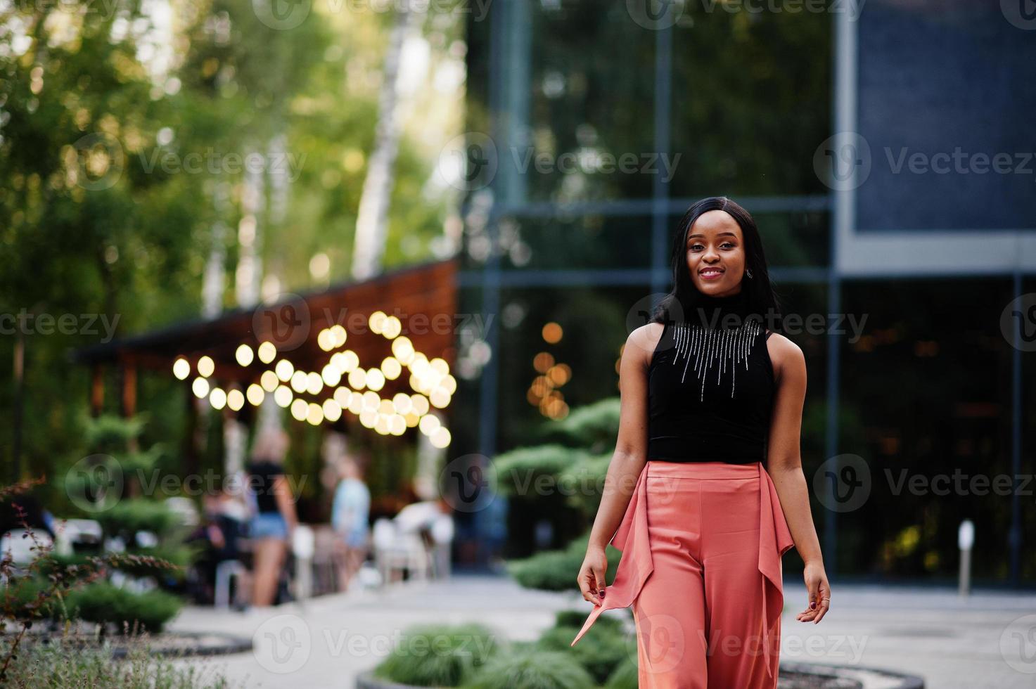 mulher afro-americana elegante em calças de pêssego e blusa preta posam ao ar livre. foto