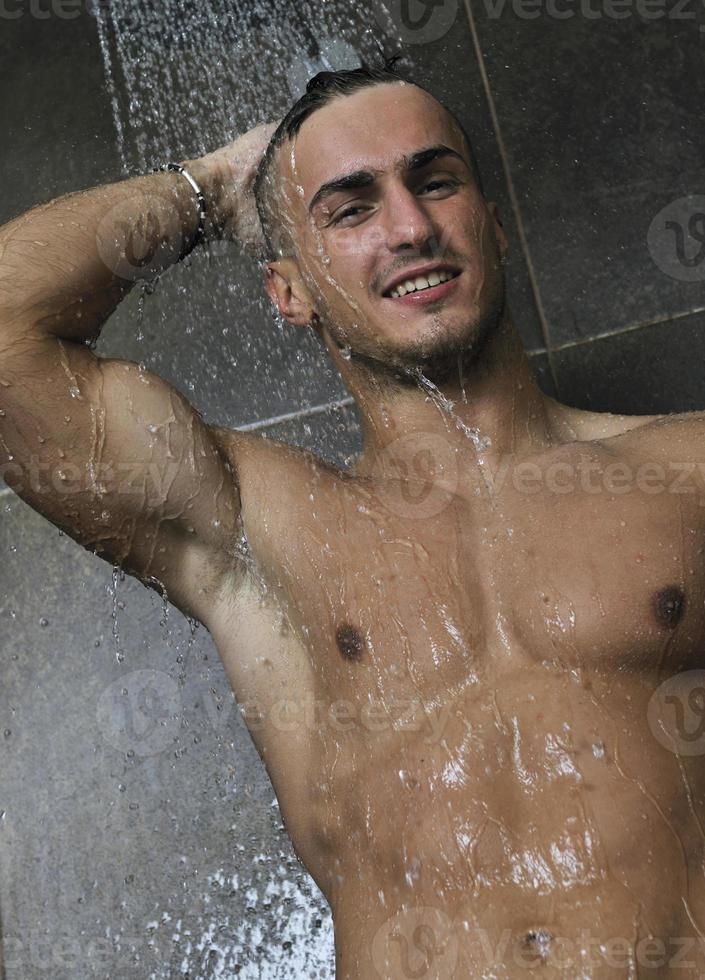 homem bonito sob o chuveiro do homem foto