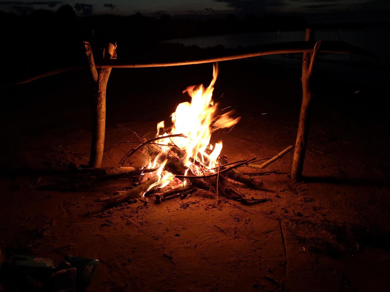 a fogueira queima à noite na margem do lago foto