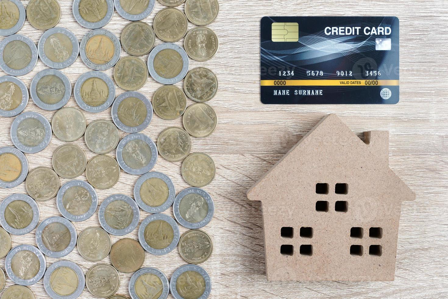 modelo de casa de vista superior e moedas com cartão de crédito na mesa de madeira foto