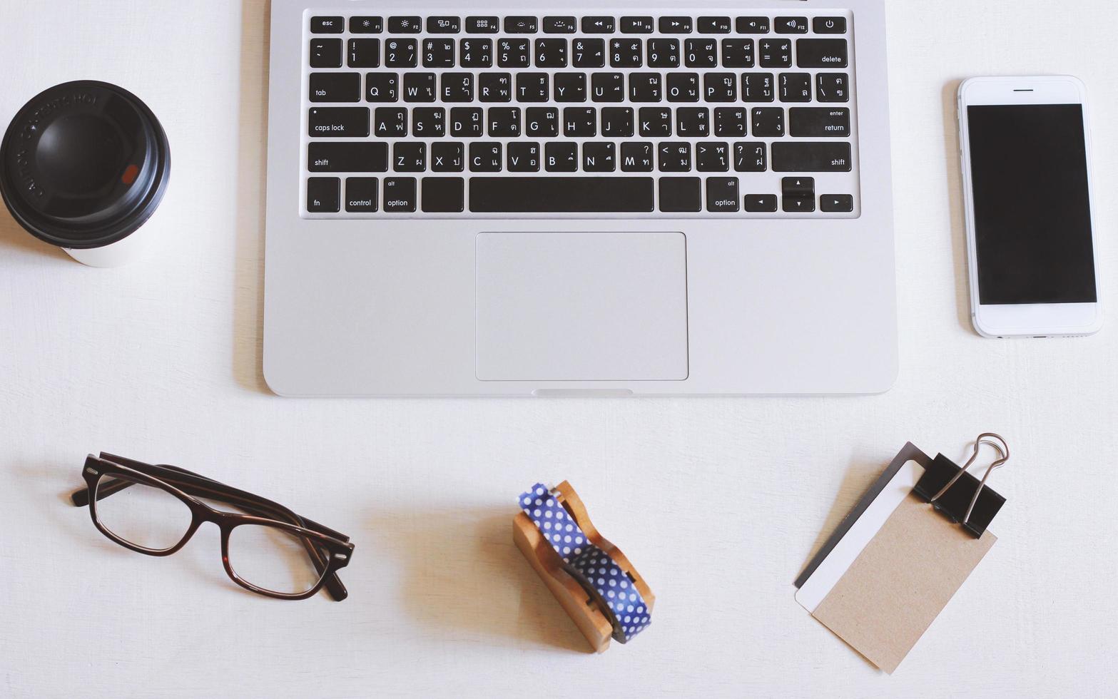 foto plana leiga da mesa do espaço de trabalho com laptop, smartphone, óculos e cartão de nome com fundo de espaço de cópia