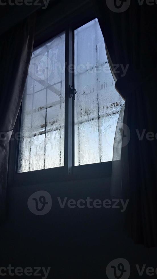 vista da janela na manhã fria com gotas de chuva de água no vidro foto