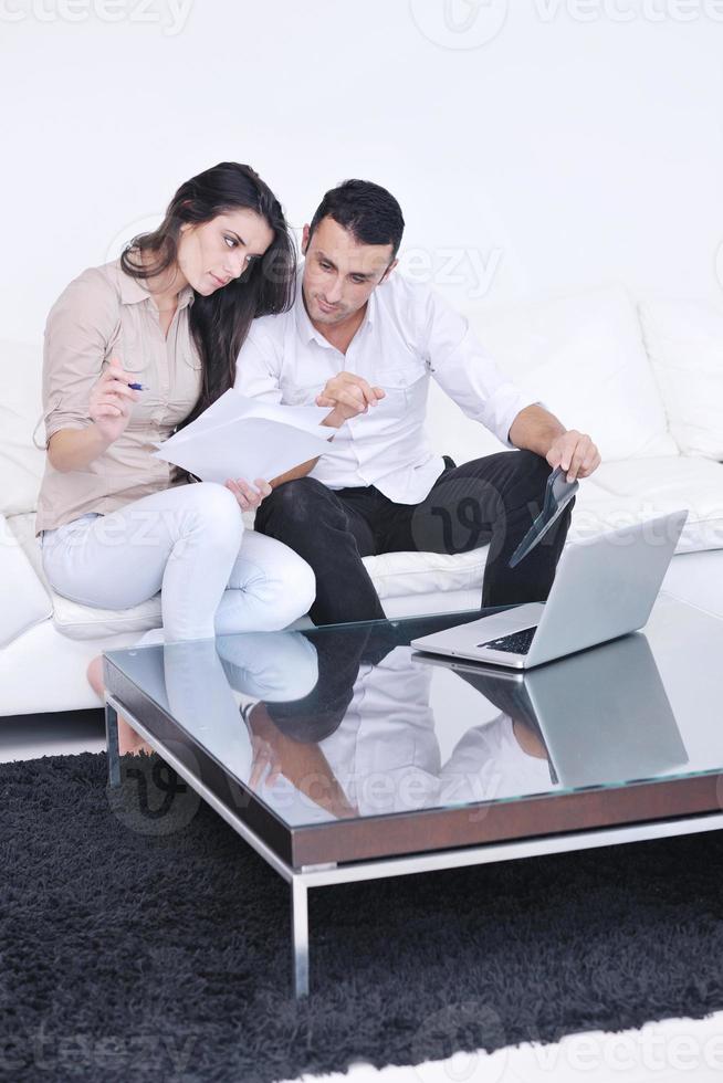 casal alegre relaxa e trabalha no computador portátil em casa moderna foto