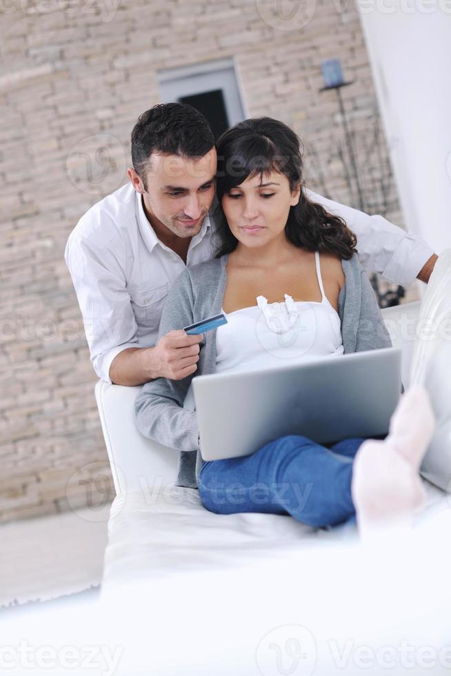 casal alegre relaxa e trabalha no computador portátil em casa moderna foto