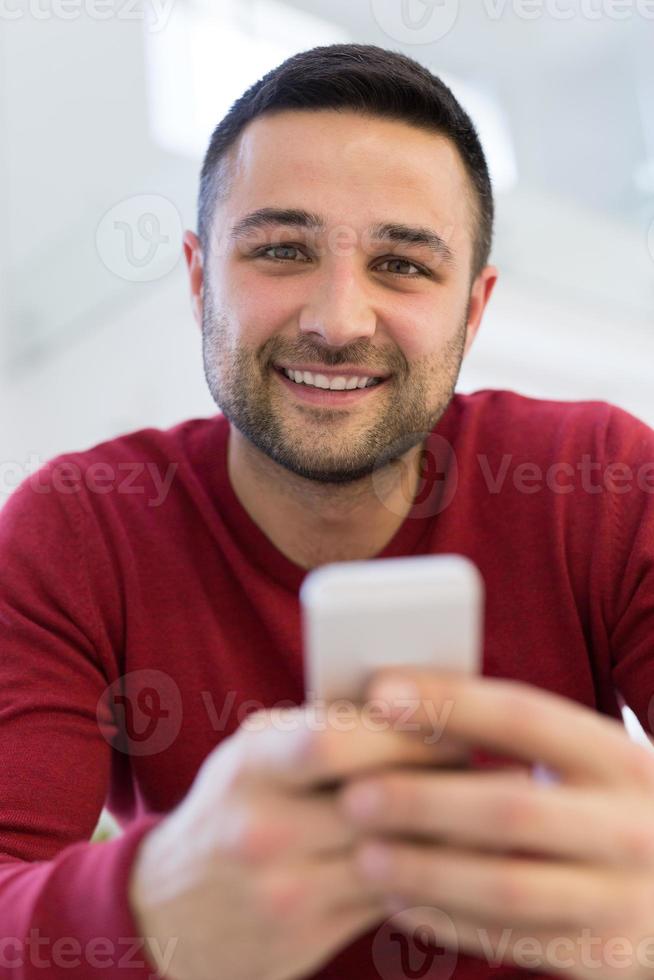 jovem usando um telefone celular em casa foto